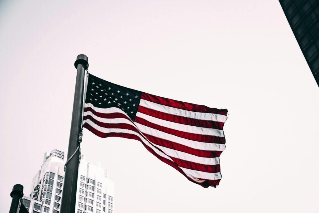 pexels-photo-2091161-2091161-1 Patriotic image of the American flag waving in the wind with city skyscrapers in the background.